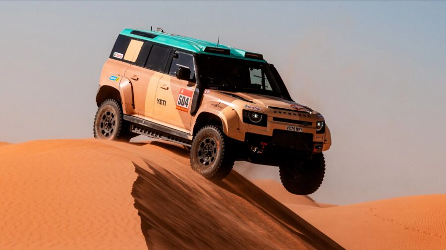 A Defender Dakar D7X-R cresting a sand dune, number 504